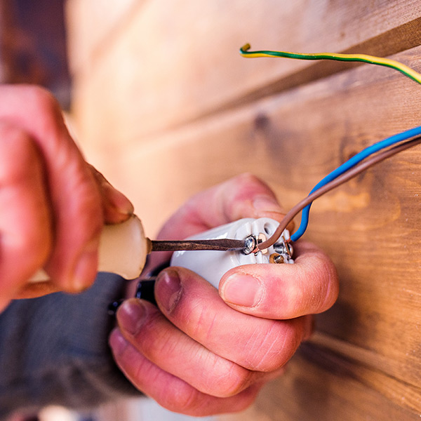 electrician working with screwdriver wooden wall